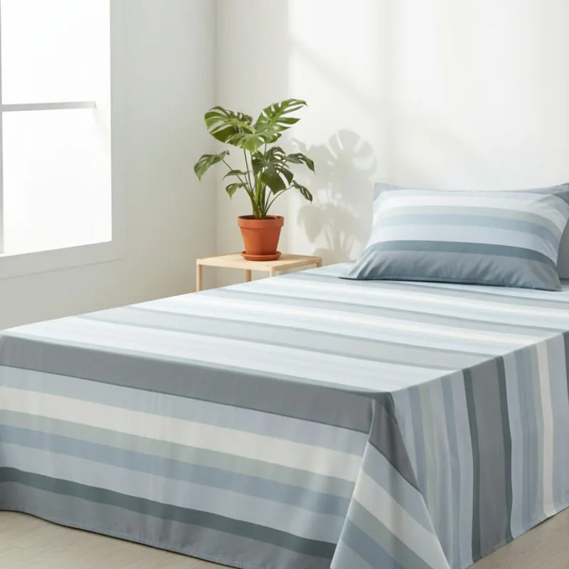 Sabanas microfibra de rayas azules y grises en una cama en habitación con ventana y planta - Sábanas baratas - Algodonea
